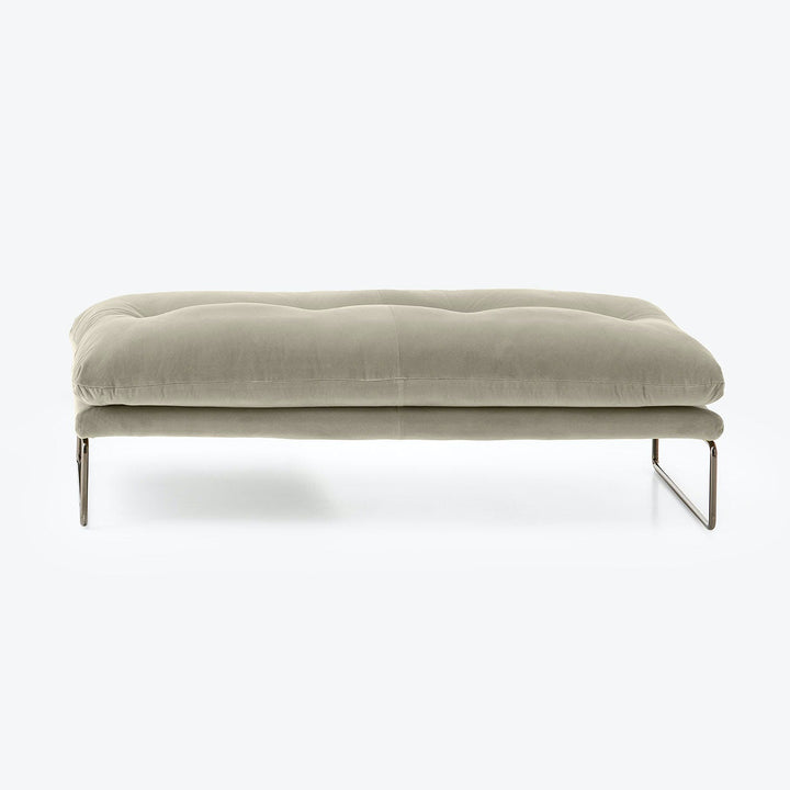 Modern minimalist ottoman with plush cushion and sleek metal legs.
