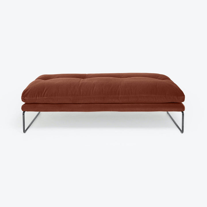 Modern ottoman with rusty upholstery and sleek metallic base design.