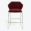 Modern bar stool with sleek metallic frame and crimson velvet upholstery.