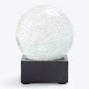 Modern and minimalist snow globe with shimmering glitter particles.