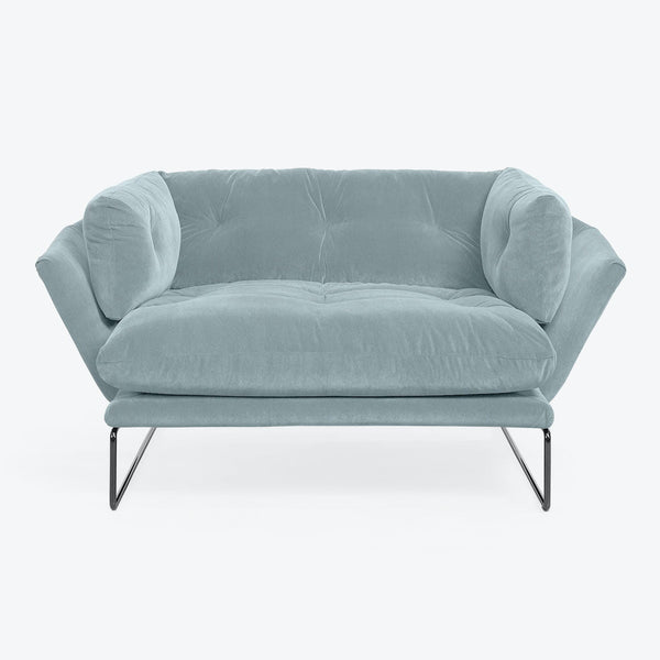 Modern blue velvet sofa with curved back and metal legs.