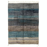 Handwoven wool rug with gradient stripes in shades of blue.