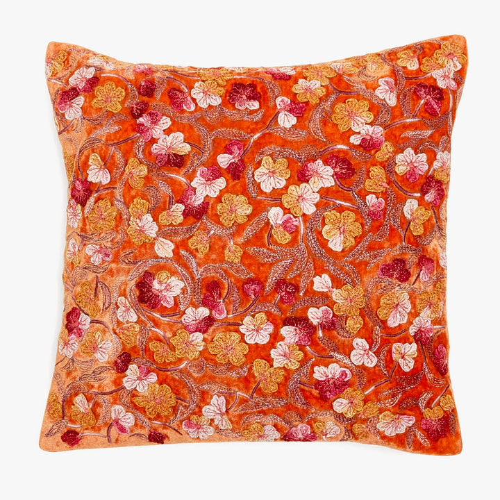 Vibrant orange decorative pillow features a lush floral design.