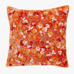 Vibrant orange decorative pillow features a lush floral design.