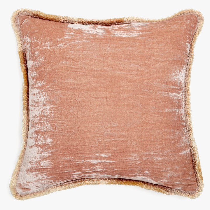 A vintage-style pink cushion with a golden-brown fringe detail.