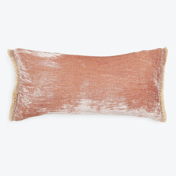 A soft, dusty rose pillow with golden fringe embellishment.