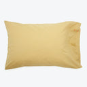 Soft yellow pillowcase on a white pillow with minor stains.