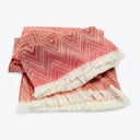 Folded red and off-white chevron textile with fringed edges.