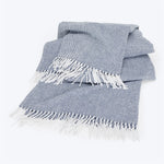 Neatly folded blue and white throw blanket with fringed edges.