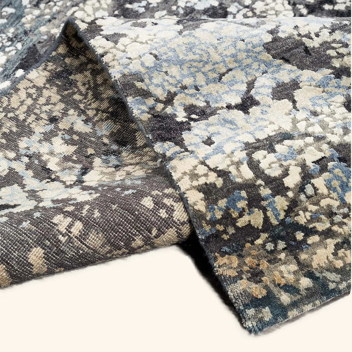Close-up of a folded patterned rug reveals intricate design and thickness.