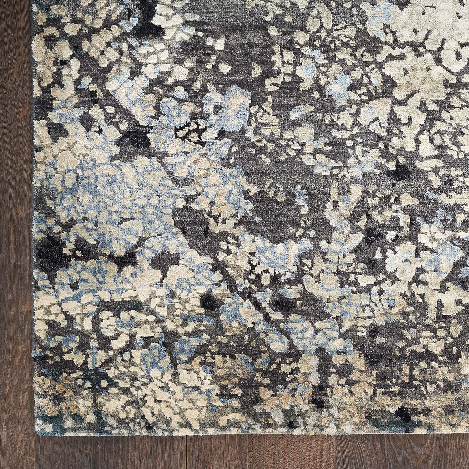 Close-up view of a modern, mottled patterned rug on hardwood.