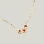 Delicate gold necklace with textured pendant and colorful gemstones.