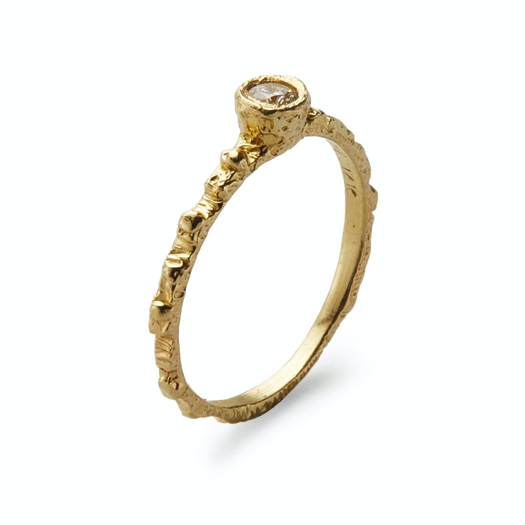 Close-up of a handcrafted gold ring with a sparkling diamond.