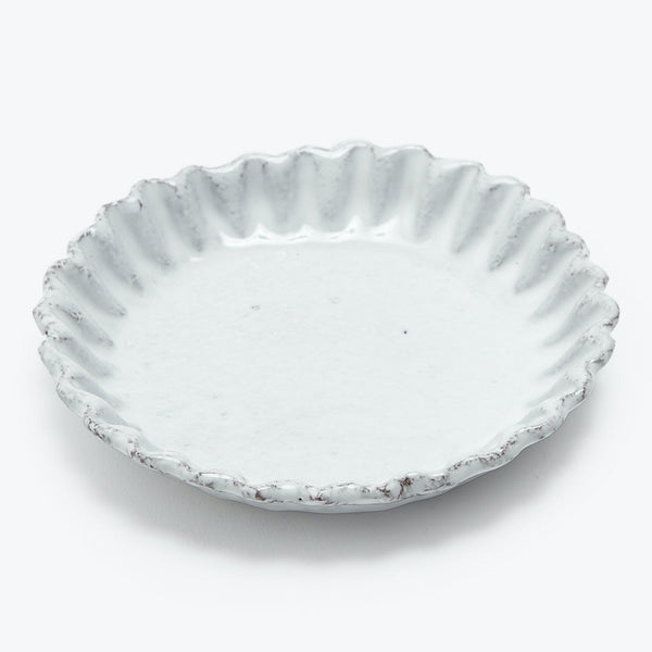 Decorative ceramic plate with fluted edge and rustic distressing.