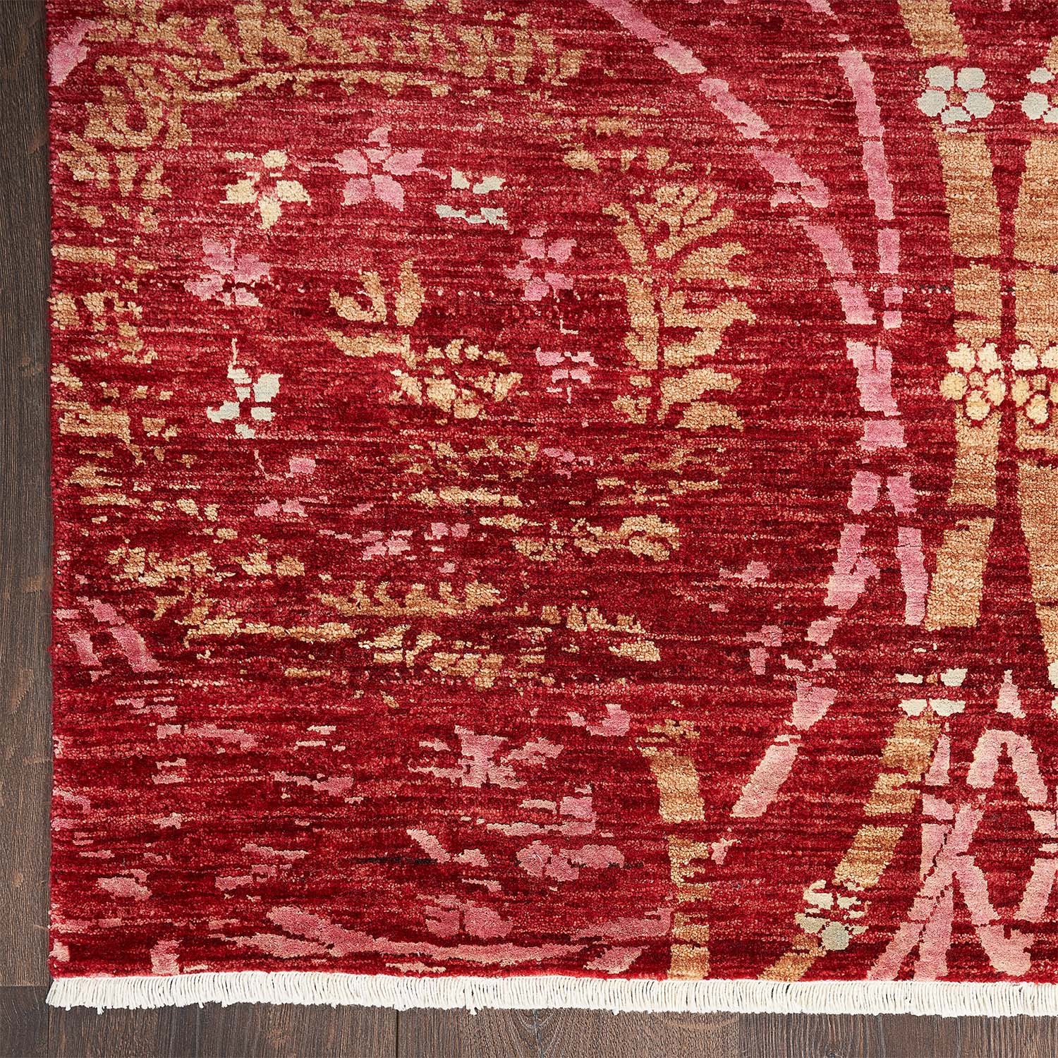 Richly designed rectangular area rug with red hues and fringe.