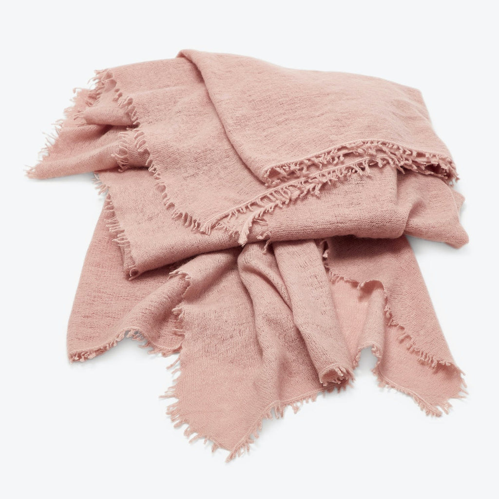Casually crumpled pink fabric with fringed edges on white background.