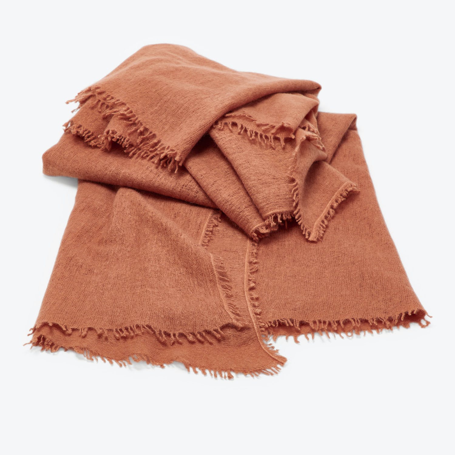 Terracotta-colored textile with woven texture and fringed edges displayed neatly.