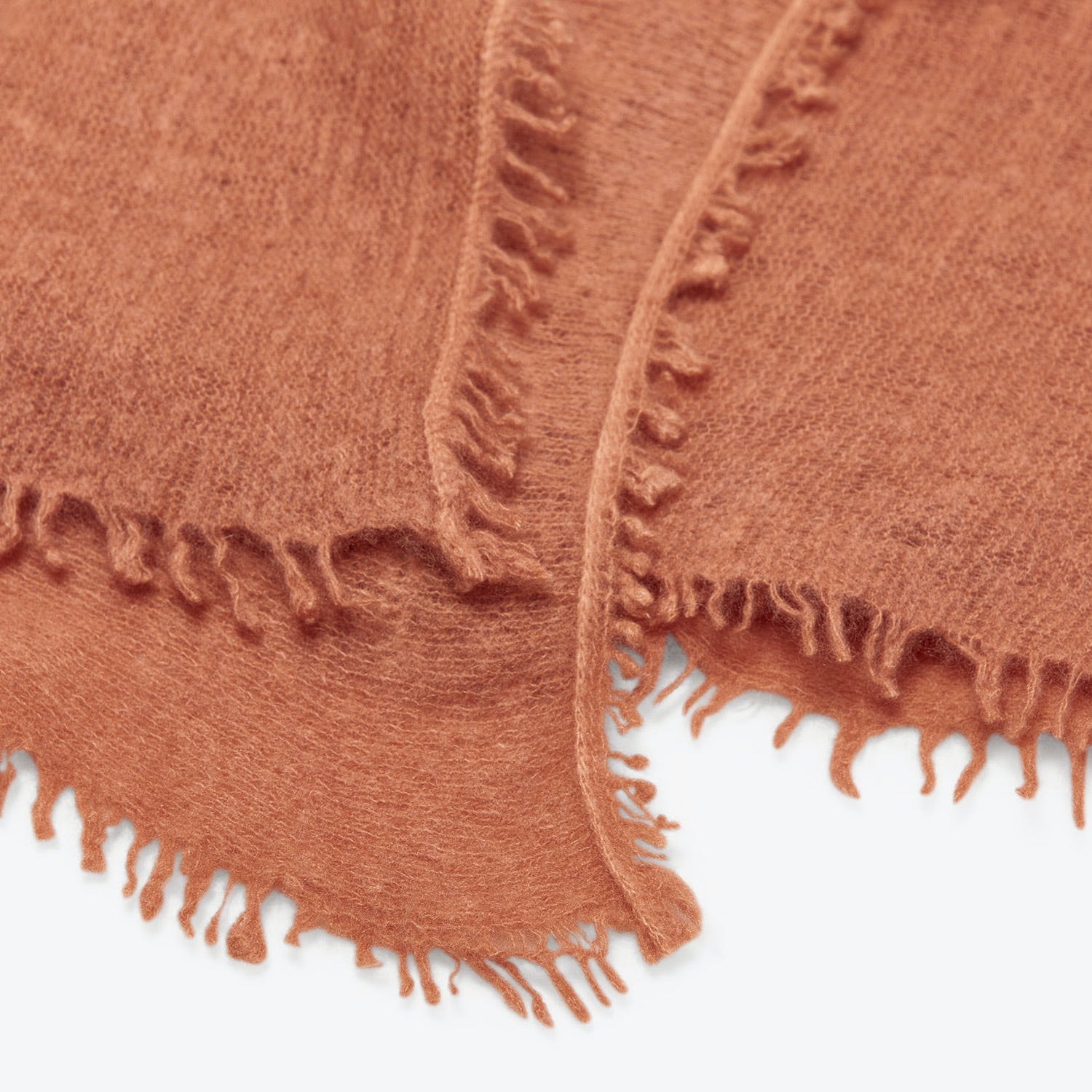 Close-up of rustic, terracotta fabric with fringed edges and fuzzy texture.