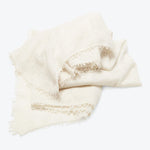 Folded cream-colored fabric with frayed edges on white background.
