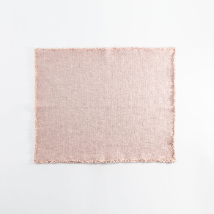 Light pink fabric square with frayed edges against white background.