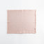 Light pink fabric square with frayed edges against white background.