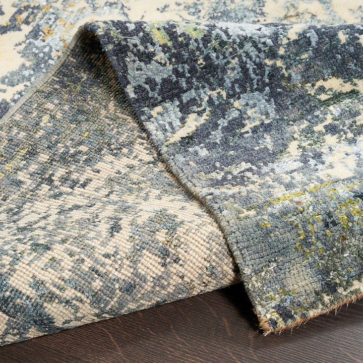 Close-up view of an abstract and colorful rug on wooden flooring.