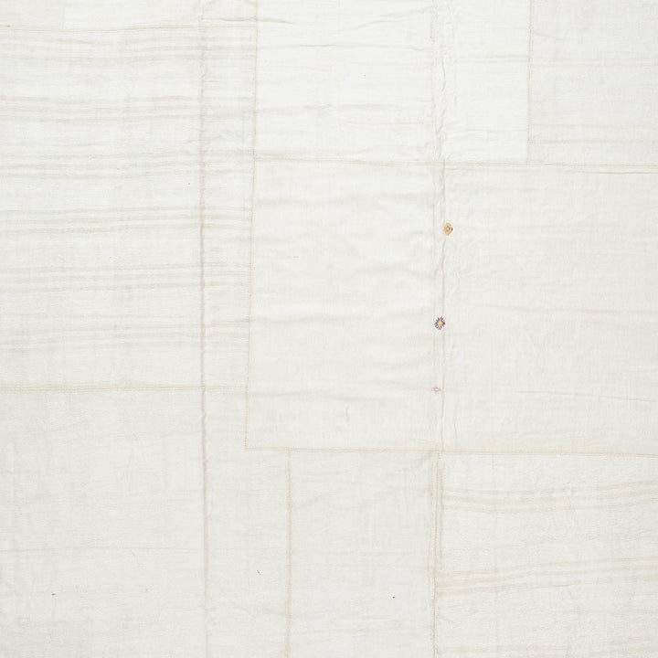 Minimalist white textile with textured panels and visible seams.