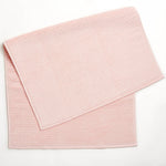 Dusty pink cloth napkins with ribbed texture on white background.