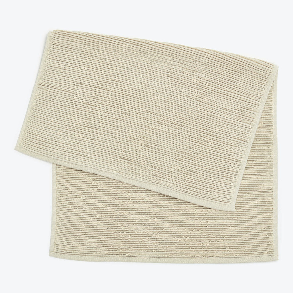 Neatly folded beige towel with ribbed texture and finished hem.