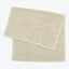 Neatly folded beige towel with ribbed texture and finished hem.