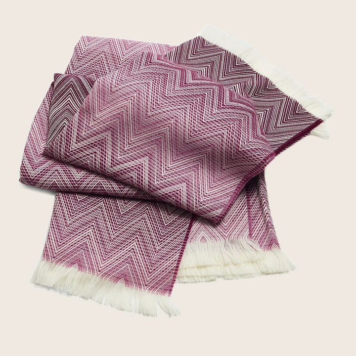 Stylish pink and white throw blanket with intricate chevron pattern.