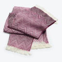 Stylish pink and white throw blanket with intricate chevron pattern.