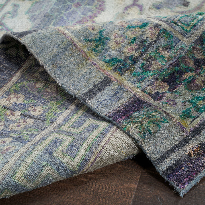 Close-up of a worn, textured rug with vibrant floral design.