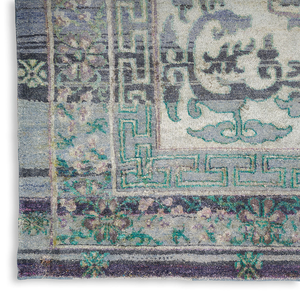 Intricate traditional rug with geometric border and floral motifs, faded colors.