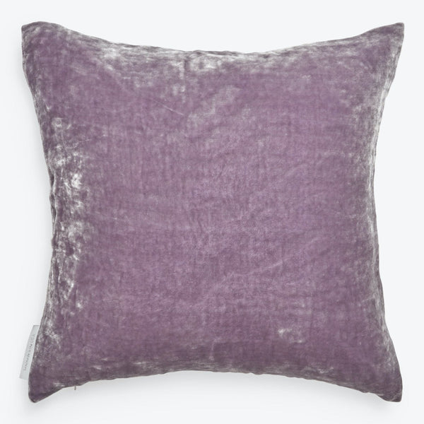 Soft purple velvet throw pillow with manufacturer's tag on side.