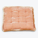 Peach plush cushion with tufted details and fringed trim.