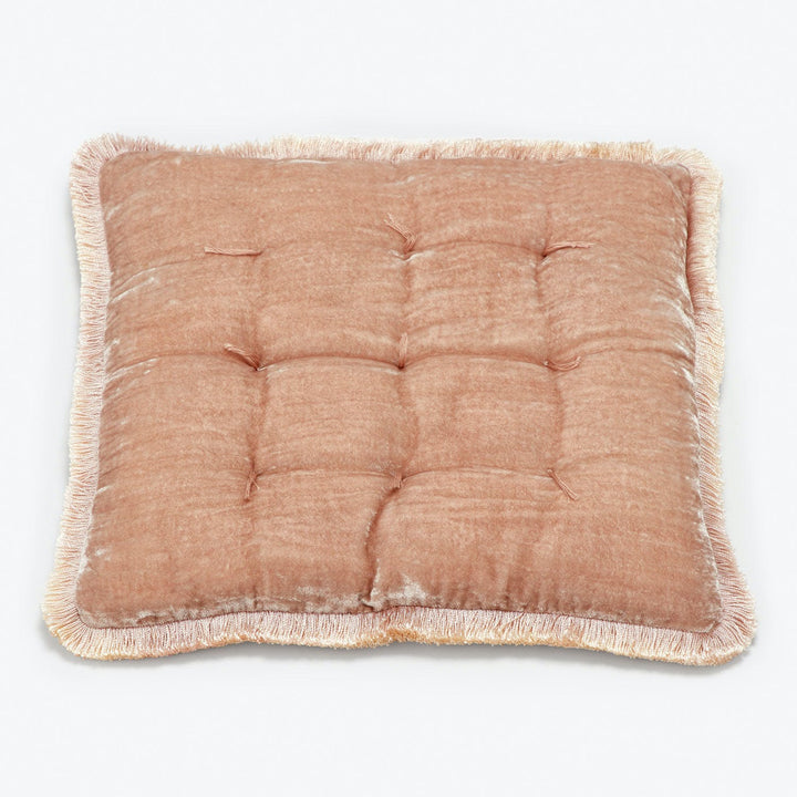Square tufted cushion with frayed fringe border in light brown.