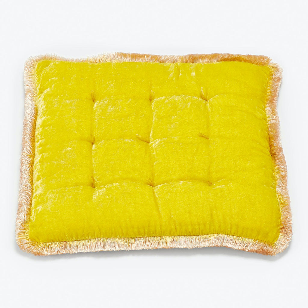 Yellow square cushion with tufting and fringed edges on white background