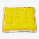 Yellow square cushion with tufting and fringed edges on white background