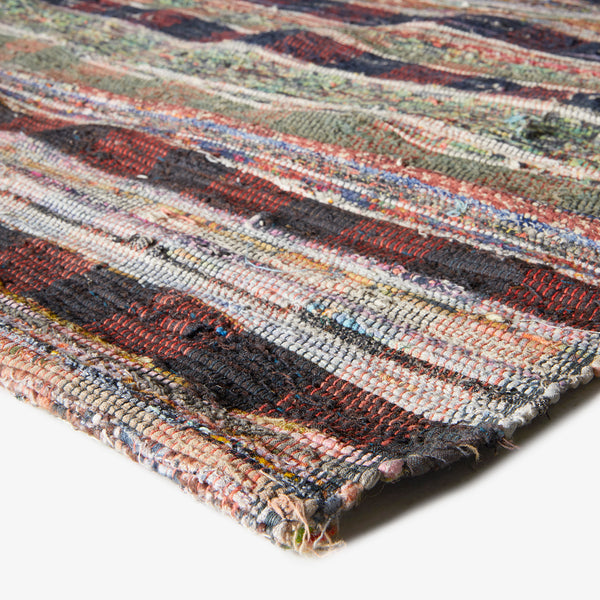 Close-up view of a textured, multi-colored rag rug with frayed edges.