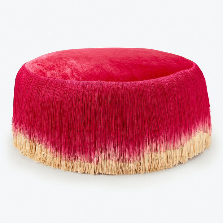 Vibrant red velvet ottoman with playful fringe, luxurious bohemian design