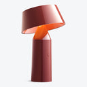 Sleek and minimalist red lamp emits warm, ambient glow.
