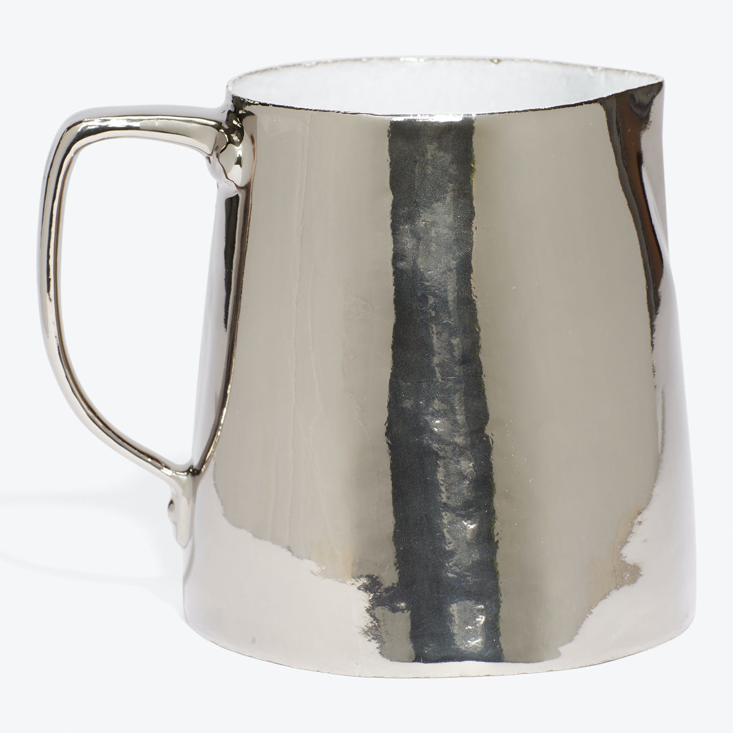 Highly reflective silver pitcher with signs of wear and tarnishing.