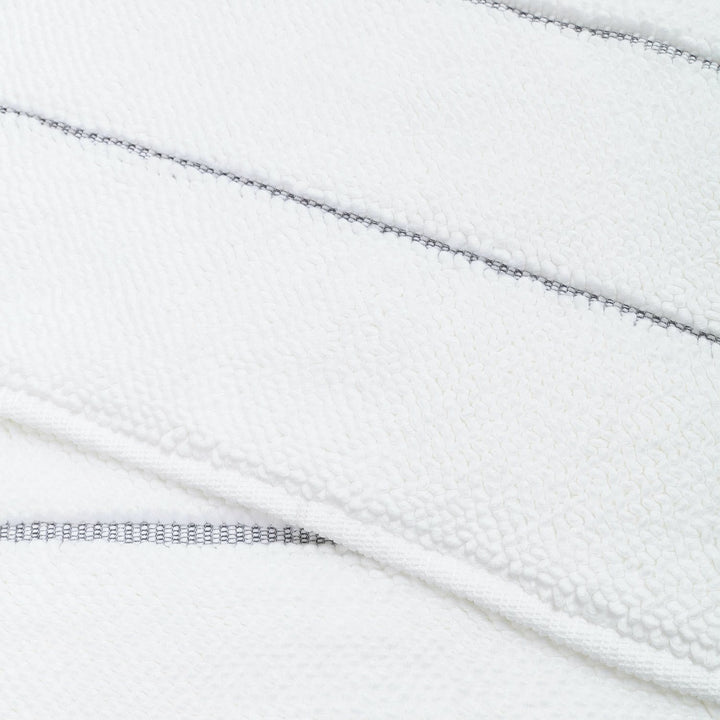 Close-up of white textured fabric with dark stitches and zipper.