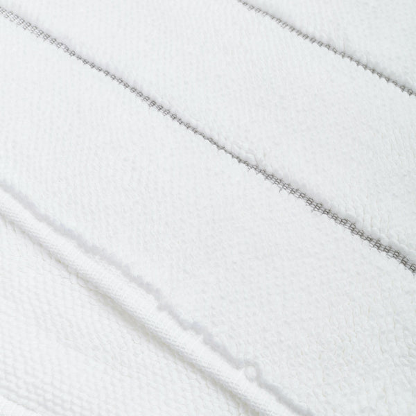 Close-up view of white terry cloth fabric with diagonal stitching.