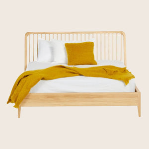 Modern wooden bed dressed in white bedding with mustard accents.