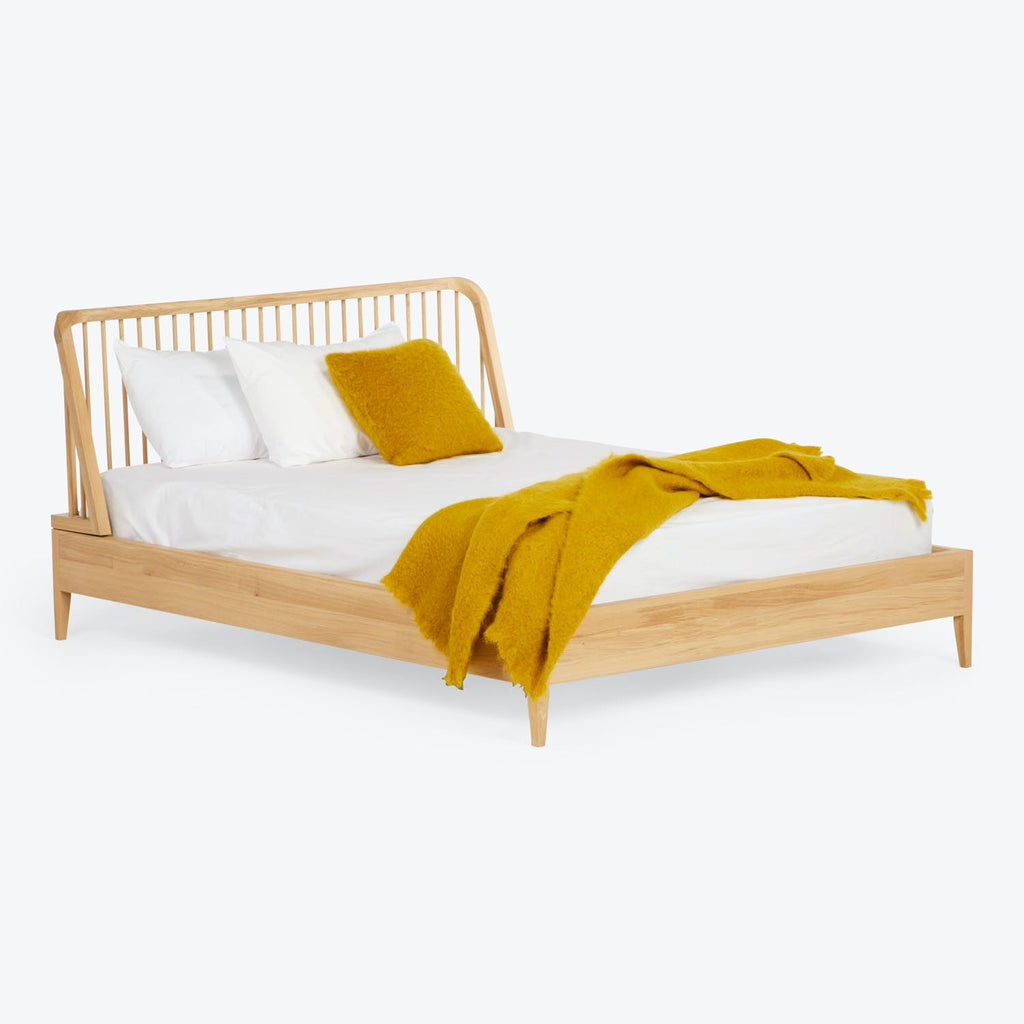 Modern wooden bed with minimalist design, dressed in white linens