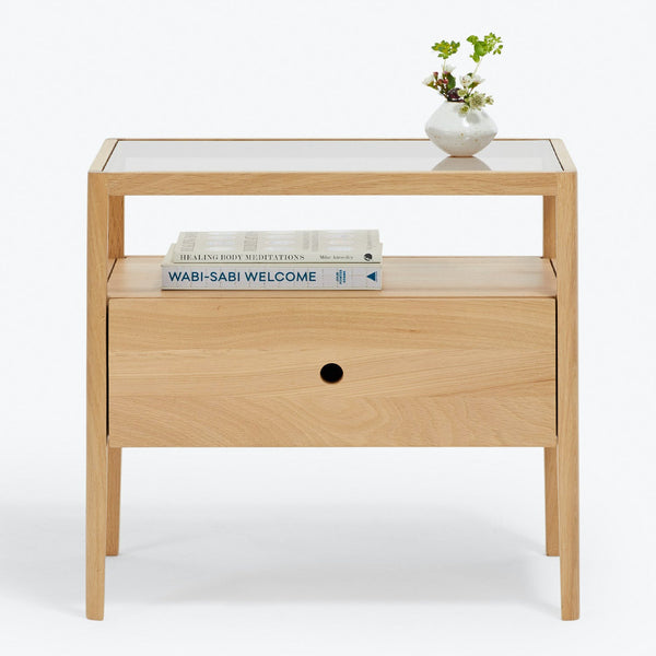 Modern, minimalist side table with glass top and wooden frame.