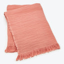 Salmon-pink textile with linen or cotton weave and fringed edges.