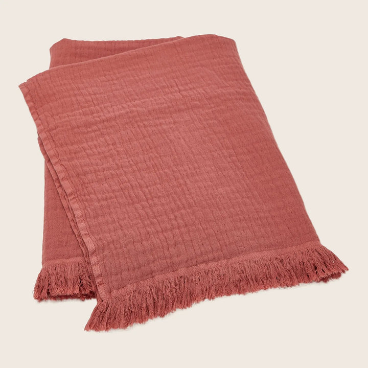 Terracotta blanket with fringed ends, perfect for cozy home decor.